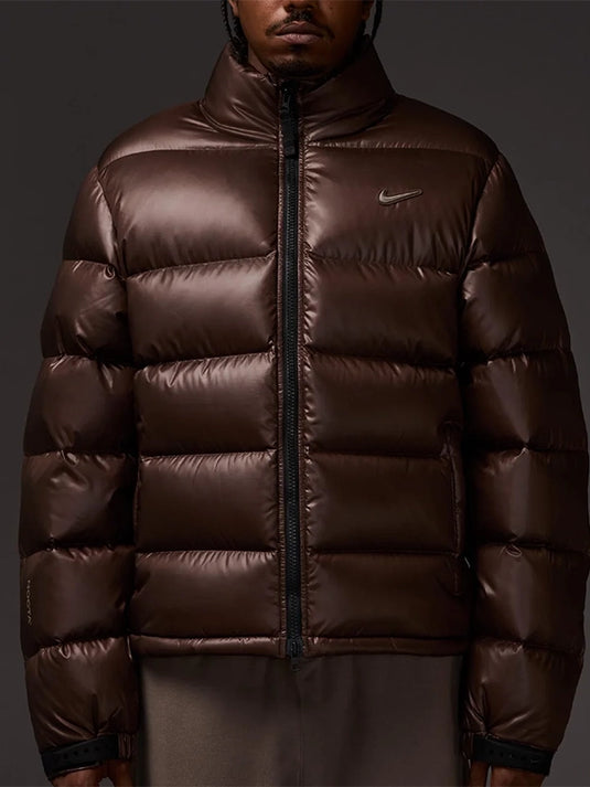 Unisex Nocta x Nike 2025 Sunset Puffer Down Jacket in brown with a warm, voluminous padded build.