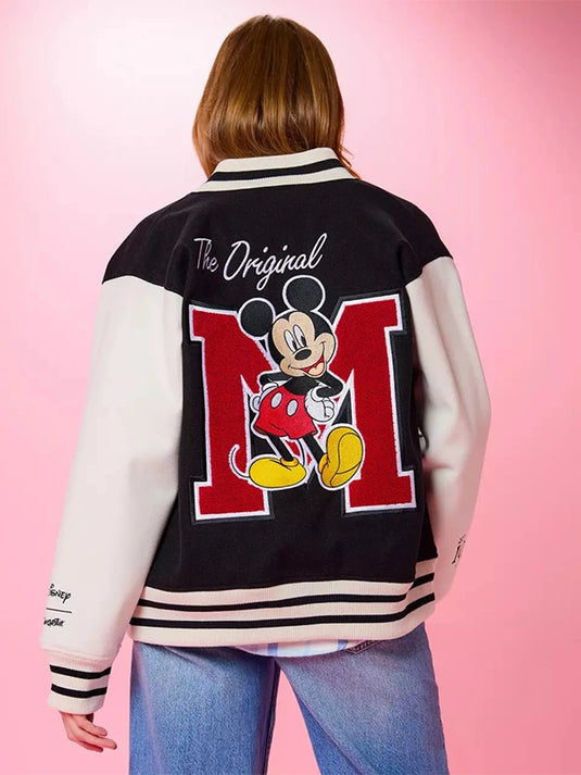 Women’s RECREATED Mickey Mouse varsity bomber jacket by Cakeworthy featuring a black body, white sleeves, and bold character styling