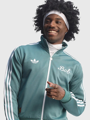 Green Adidas x Bob Marley 2026 Football Is Freedom track jacket recreated with bold graphic elements and unisex athletic tailoring.